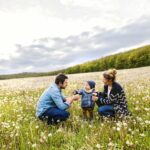 Cute little boy with parents in dandelion field