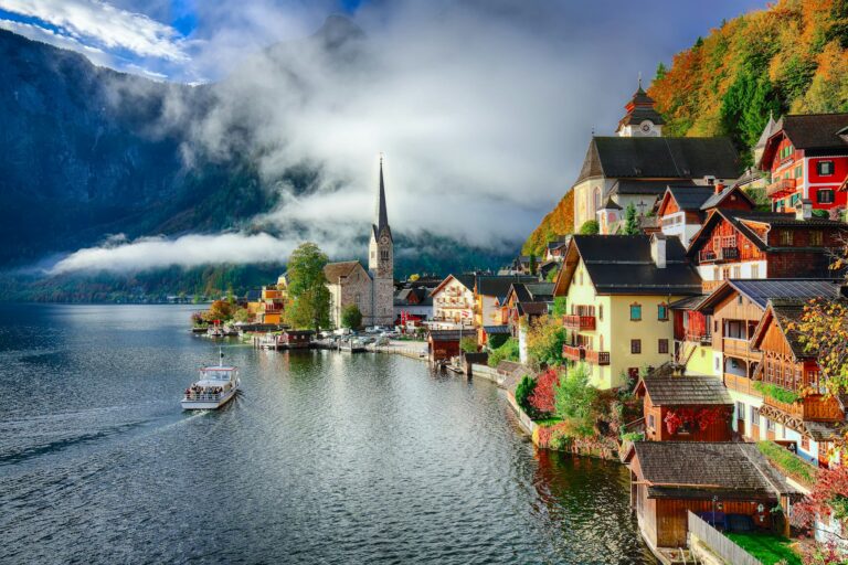 Foggy autumnal sunrise at famous Hallstatt lakeside town reflect