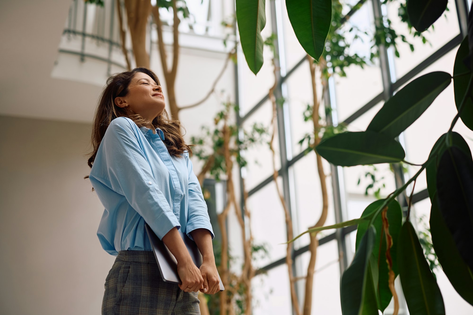 Satisfied businesswoman with eyes closed in office hallway.