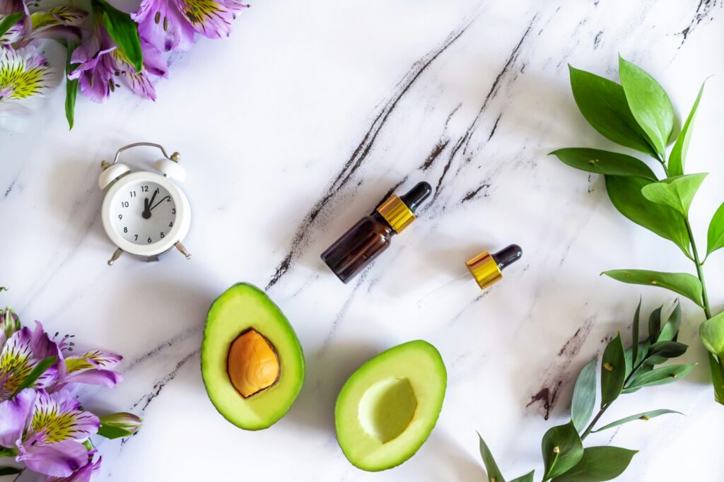 Flat lay composition of natural cosmetics for face skin care, serum and avocado. Top view