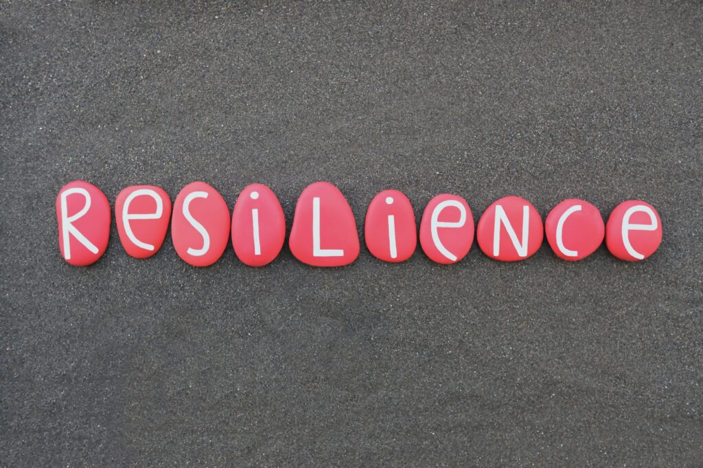 Resilience word composed with red colored stone letters over black volcanic sand