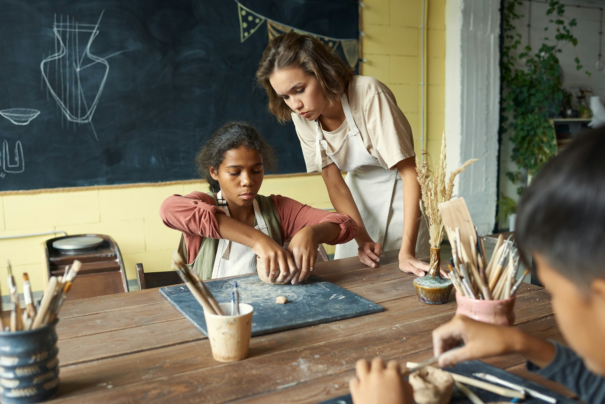 Young teacher of handcraft helping one of pupils at lesson